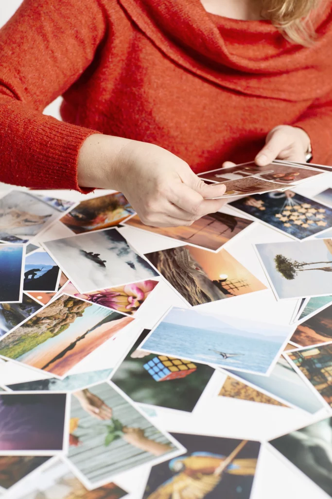 Photo d'Amandine déposant des cartes postales différentes sur une table. Des images qui peuvent aider des personnes à décrire leur état d'être